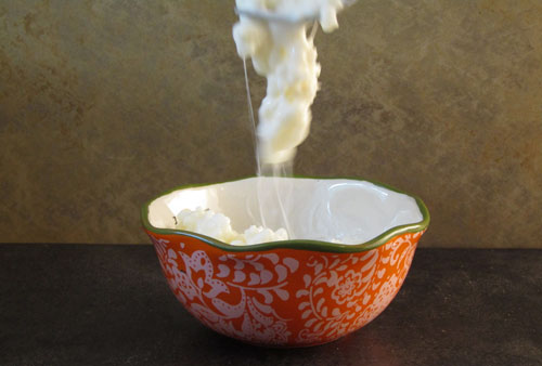 Slimy kefir grains falling into a bowl