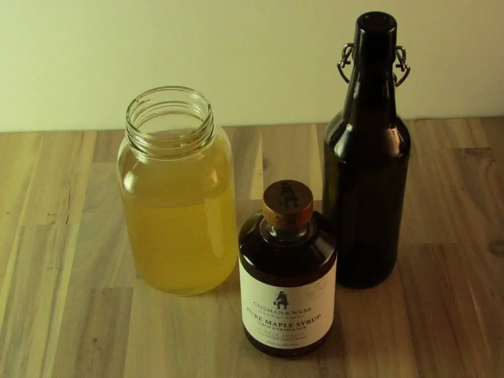 Bottle of maple syrop a mason jar of kombucha and an empty swing top bottle