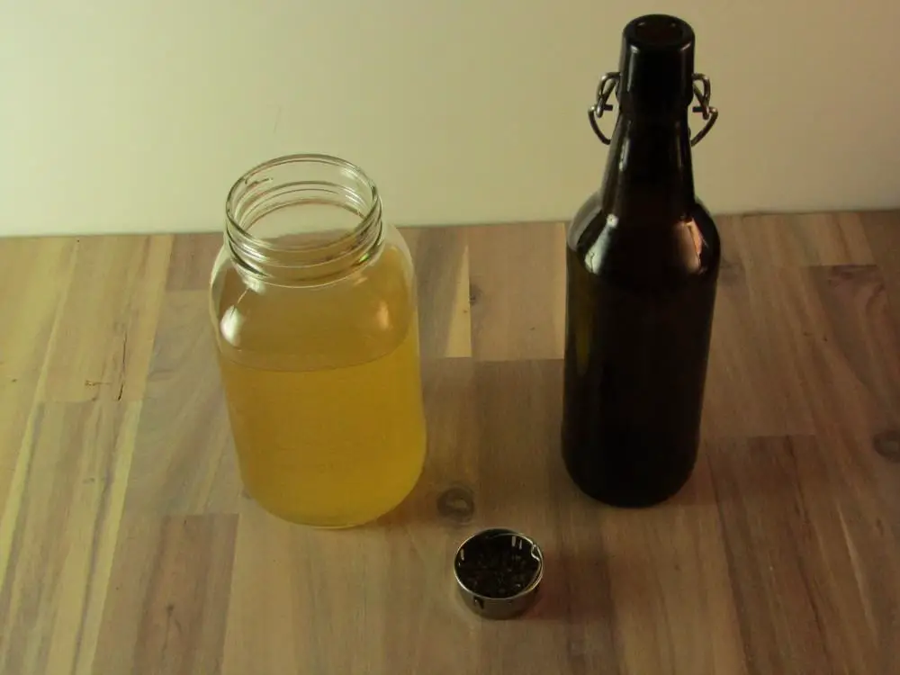 Small cntainer of dried pepermint with a mason jar of kombucha and an empty swing top bottle