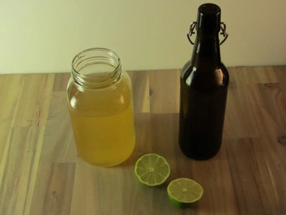 A halved lime with a mason jar of kombucha and an empty swing top bottle