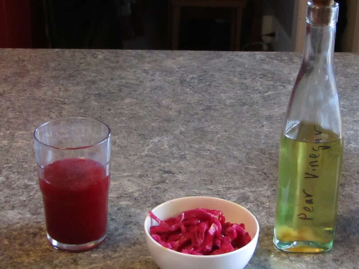 Glass of Blueberry kombucha, bowl of sauerkraut and a bottle of pear vinegar