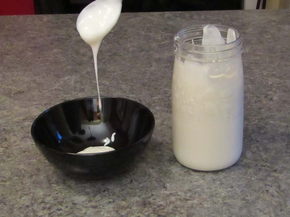 slimy yogurt falling from a spoon into a black bowl