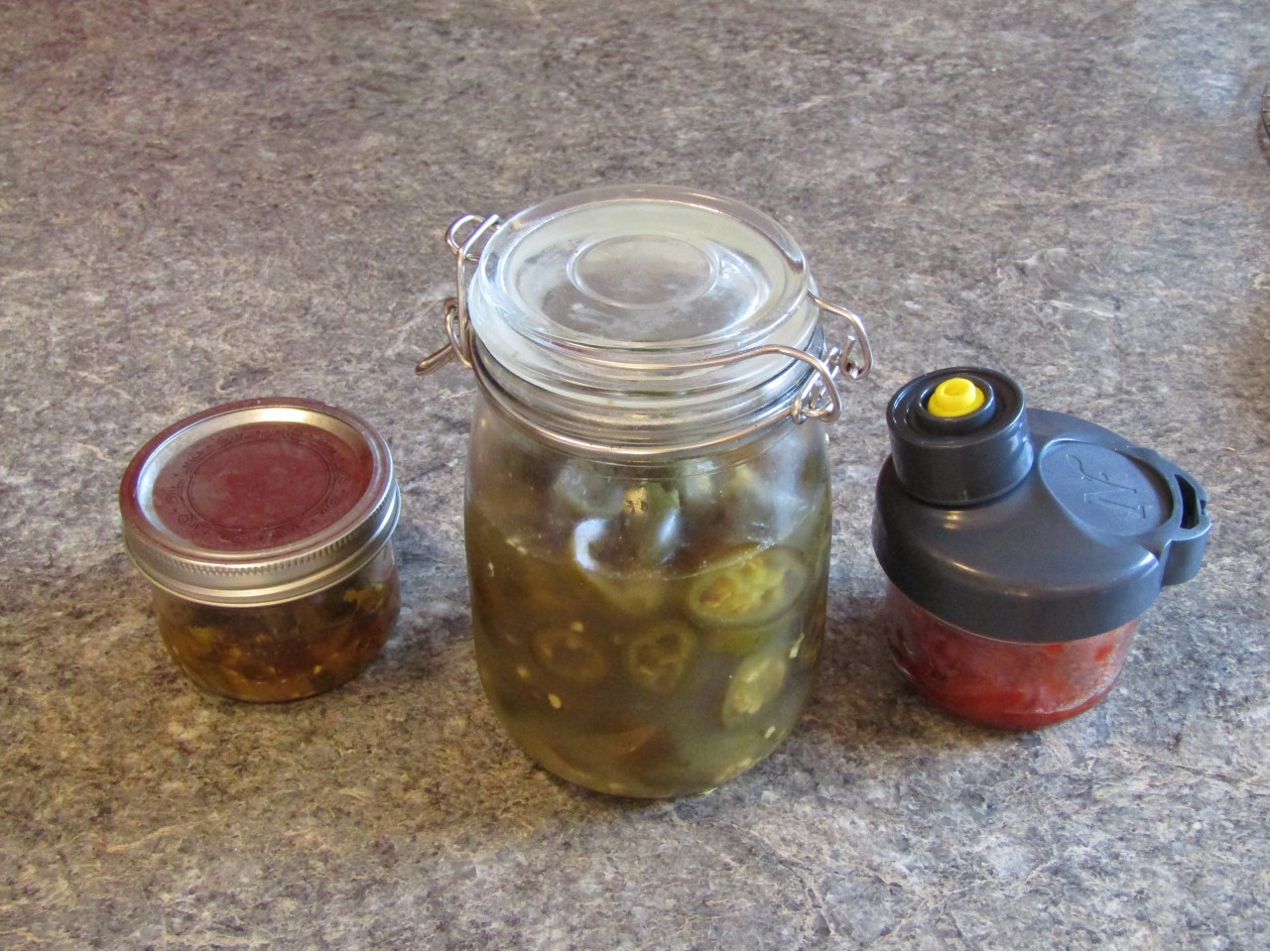 Three differnet types of fermented peppers in three different containers
