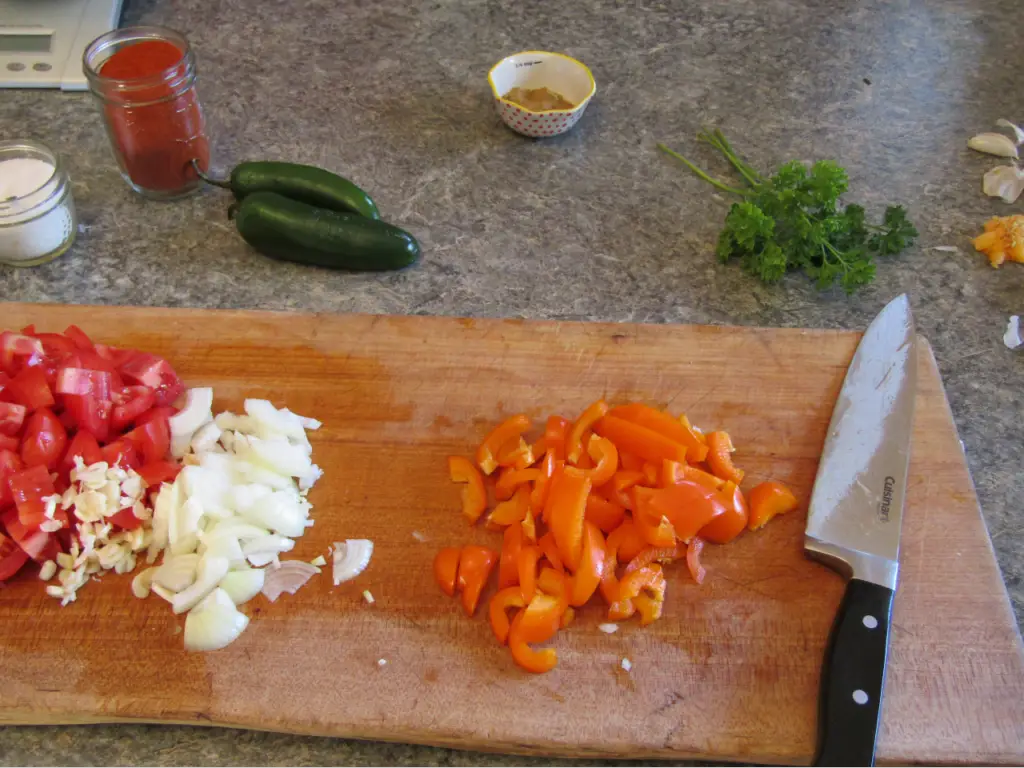 Chopped orange bell pepper on a cutting board with knife and other vegetables