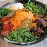 Bowl filled with taco salad with cheese on top