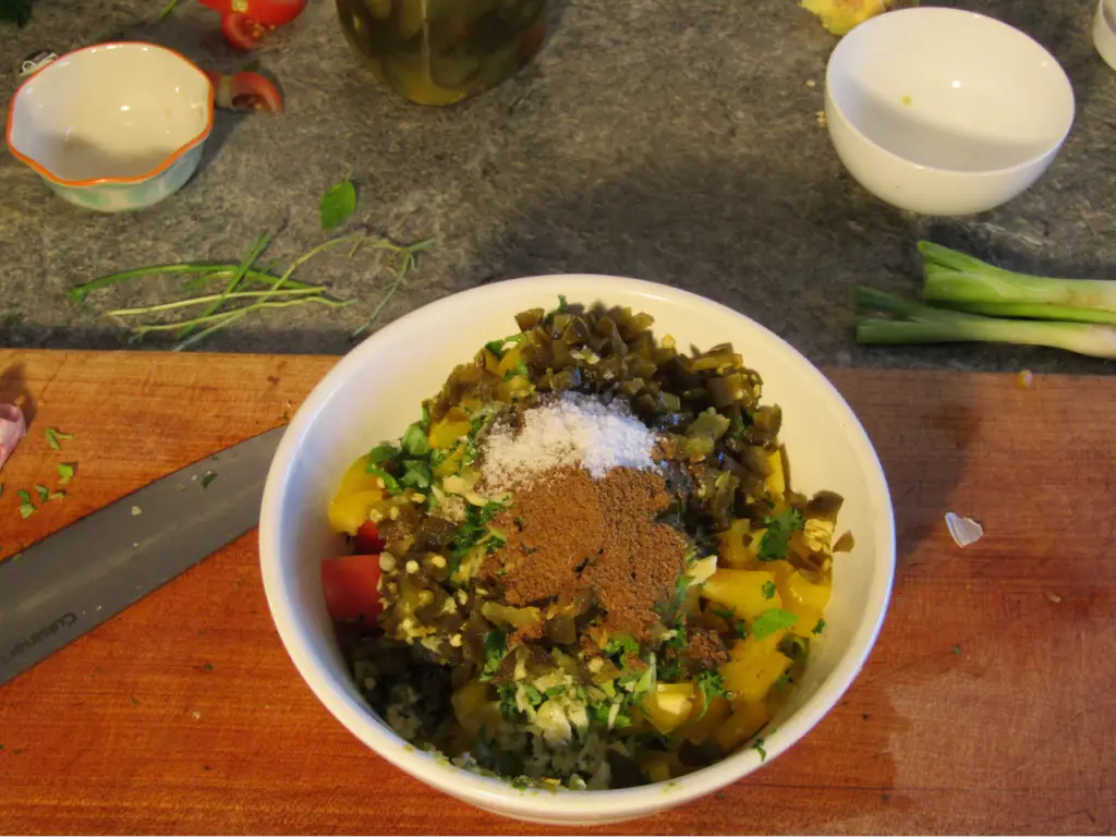 Bowl of fresh salsa ingredients with a tablespoon of cumin on top
