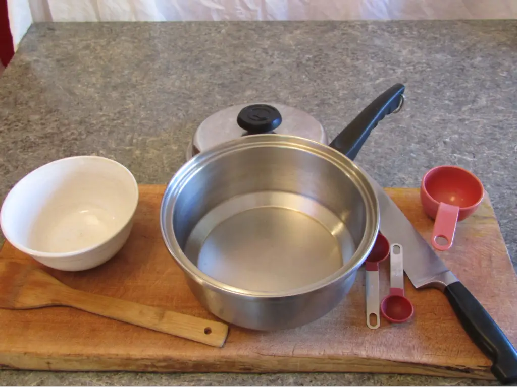 equipment for making chili with fermented hot peppers: a cutting board, kitchen knife mixing bowl, steel pot wooden spoon and various measuring spoons