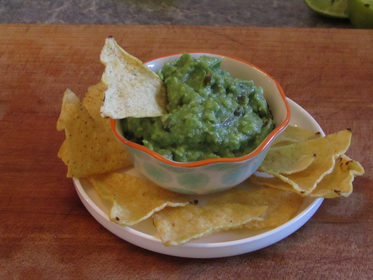 bowl of guacamole on a plate filled with corn chips