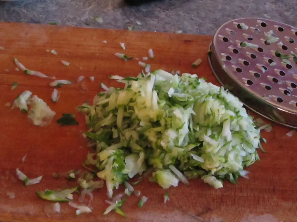 Grated cucumber on a cutting board with grater in background