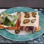 an open faced sandwich made from almond flour waffles, beef, cheese topped with fermented jalapeno peppers and lettuce