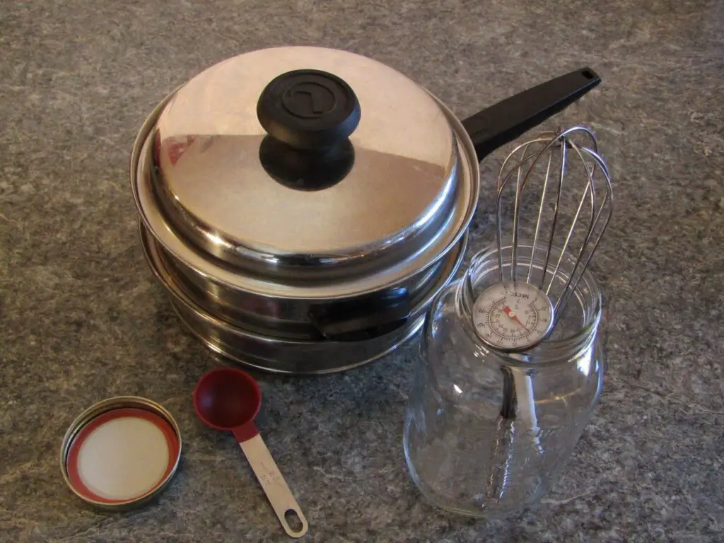 Equipment needed to make yogurt with added powdered milk: double boiler, glass mason jar with lid,  whisk, thermometer and a measuring spoon