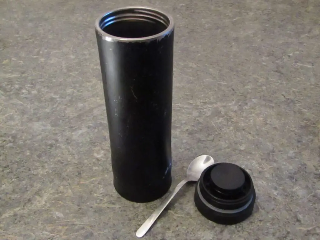 A spoon and a black thermos with lid