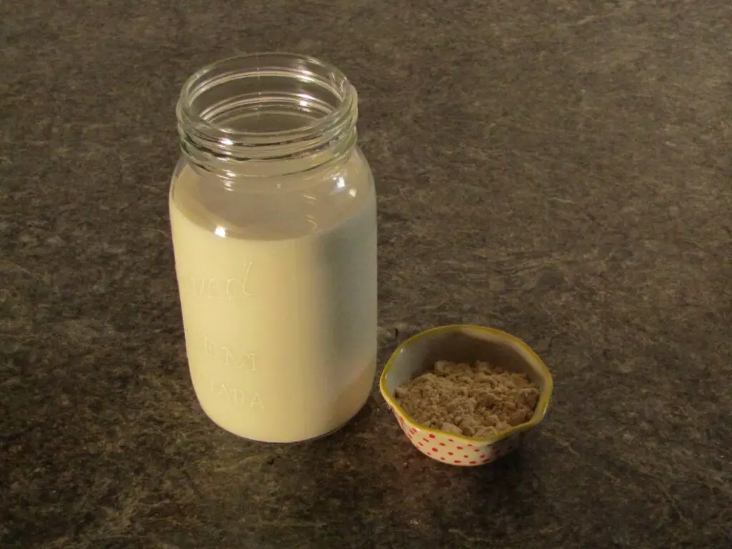 Jar of milk with protein powder in small bowl sitting beside it